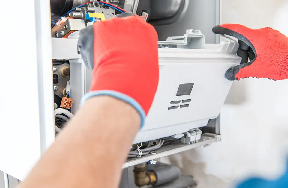 Commercial gas engineer servicing a gas appliance with red gloves