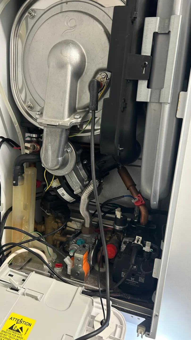 Inside of an opened boiler showing the heat exchanger, wiring and control board