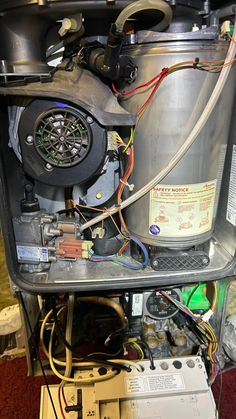 Boiler internals showing the fan, heat exchanger cylinder and gas valve during servicing