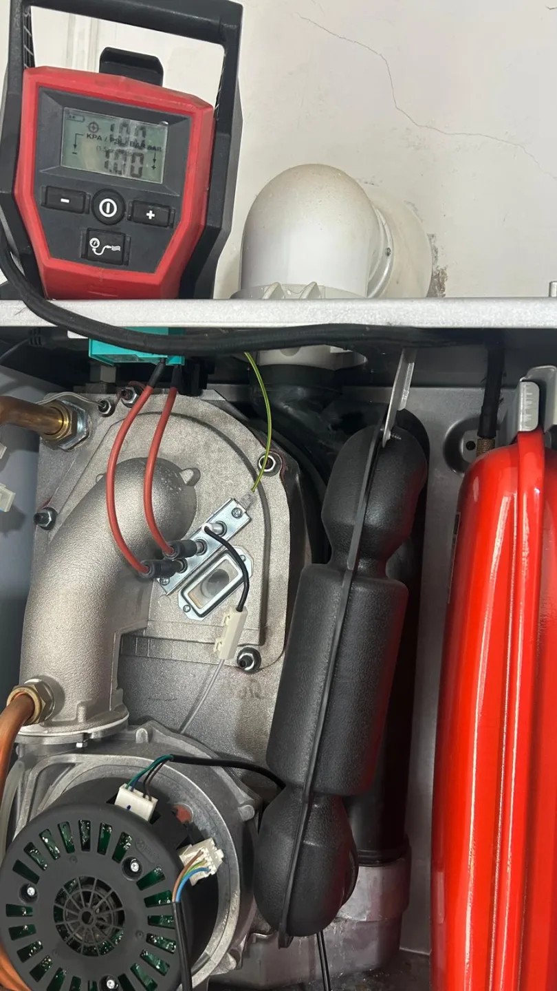 Boiler internals with the fan, expansion vessel and gas pipework exposed during a service