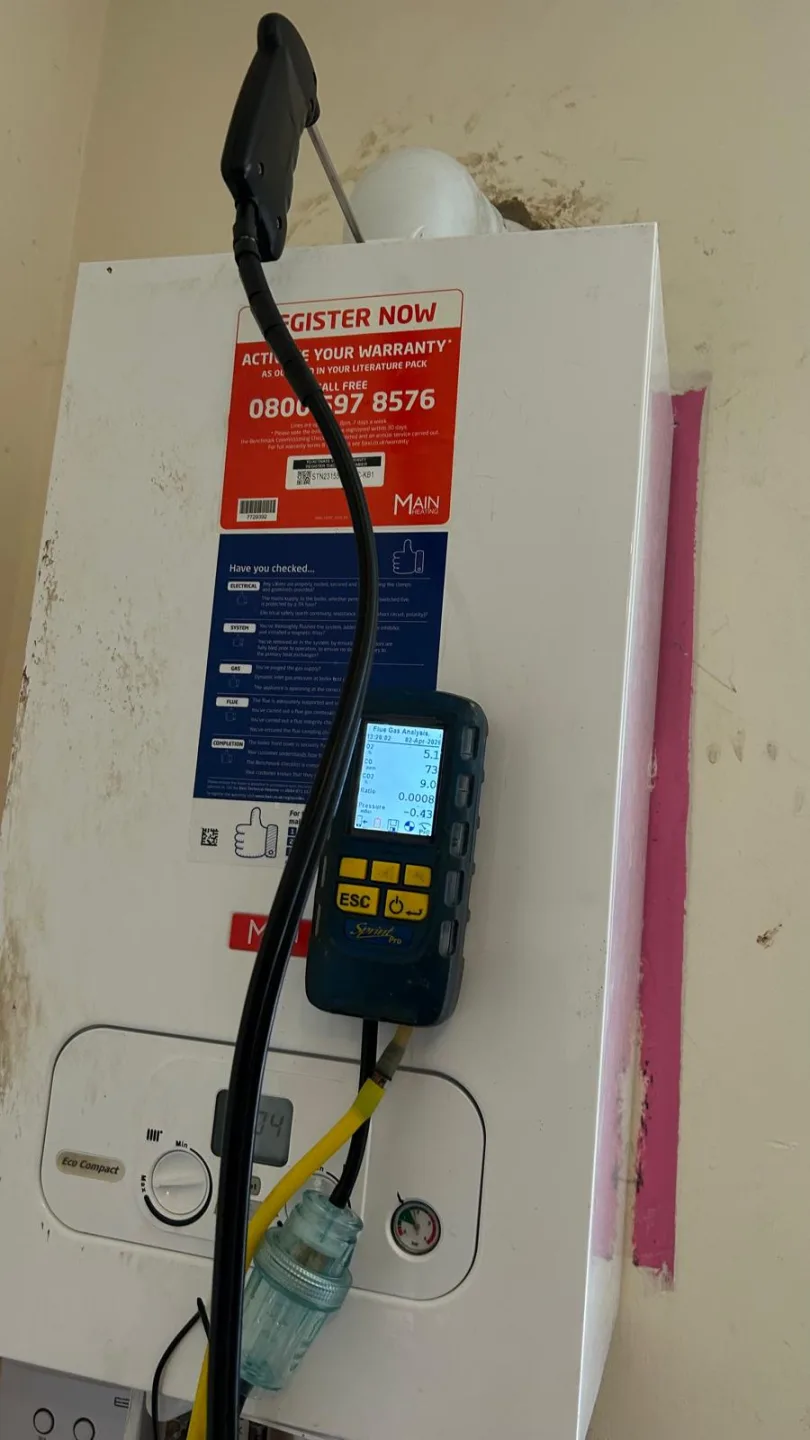 Gas analyser held against a boiler carrying its warranty registration sticker during testing