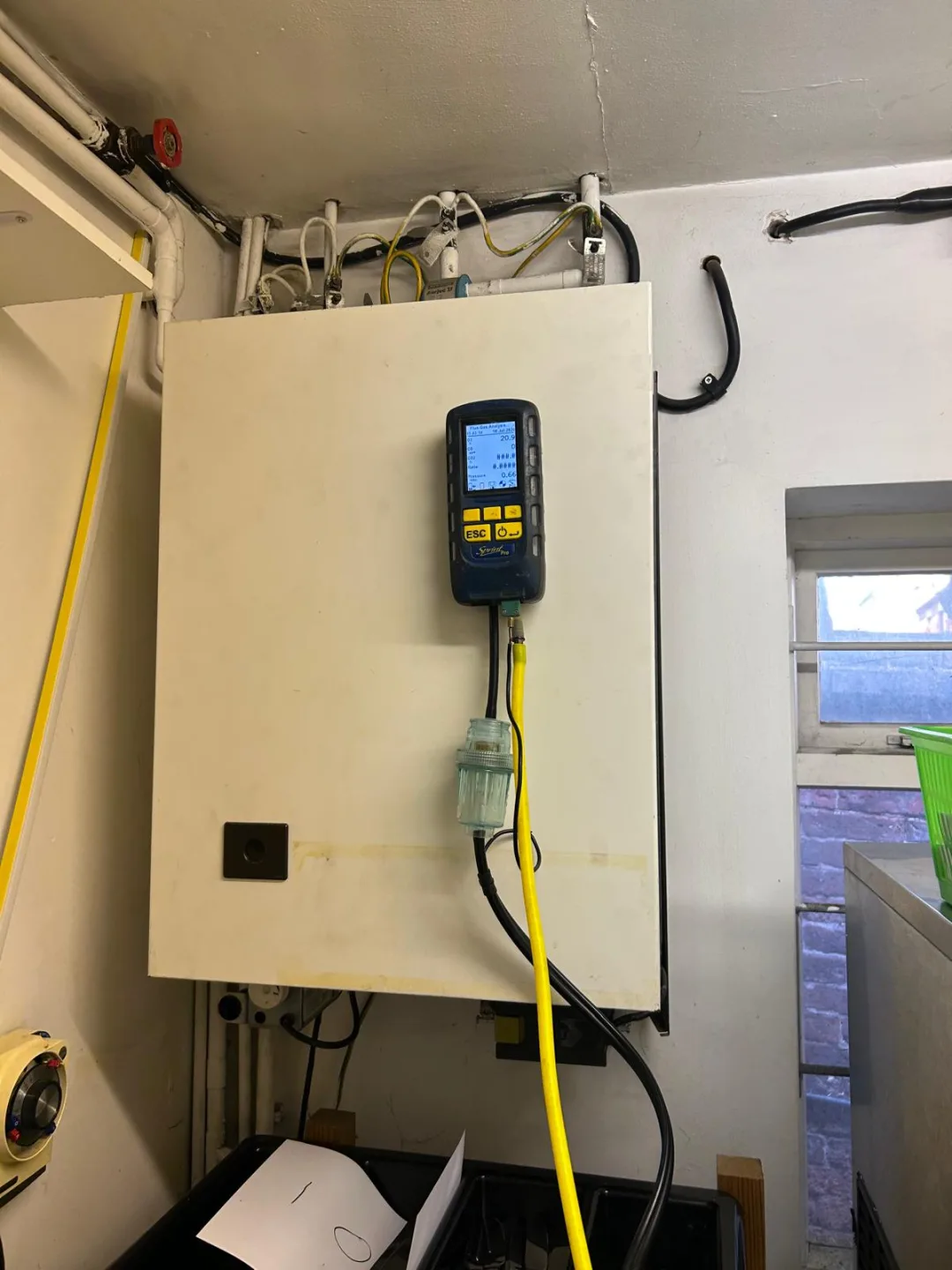 Analyser attached to an older cream-cased boiler in a utility area