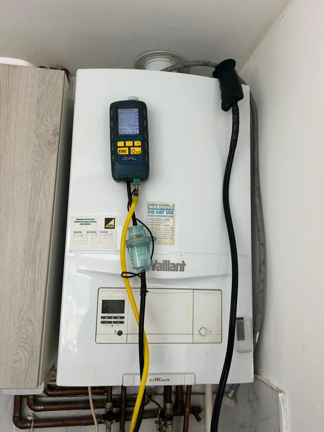 Analyser probe connected to a Vaillant combi boiler in a narrow cupboard during a service