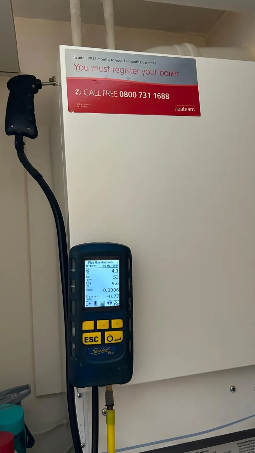 Analyser hooked onto a boiler carrying its registration notice, sampling in progress