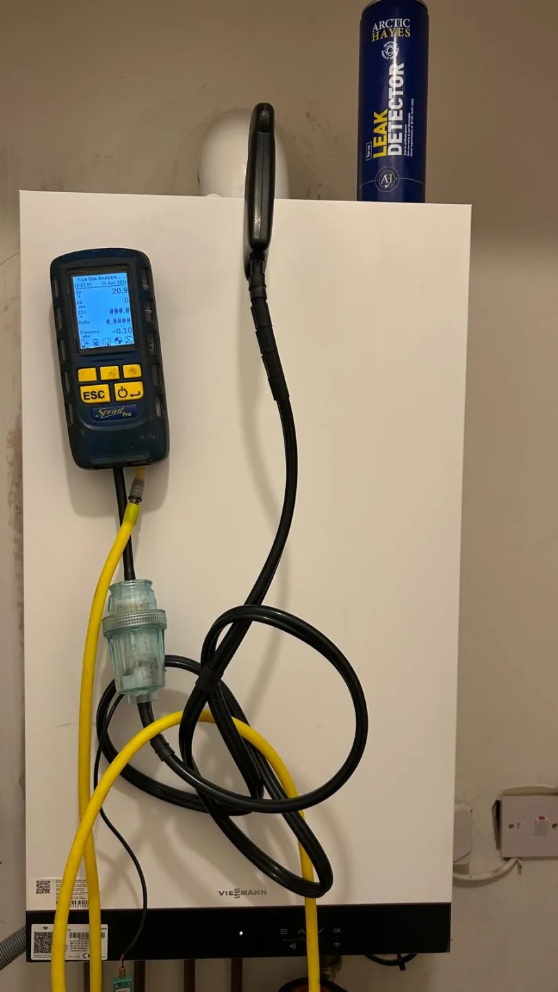 Analyser mounted on the front of a boiler with its sampling hose coiled below, mid-service
