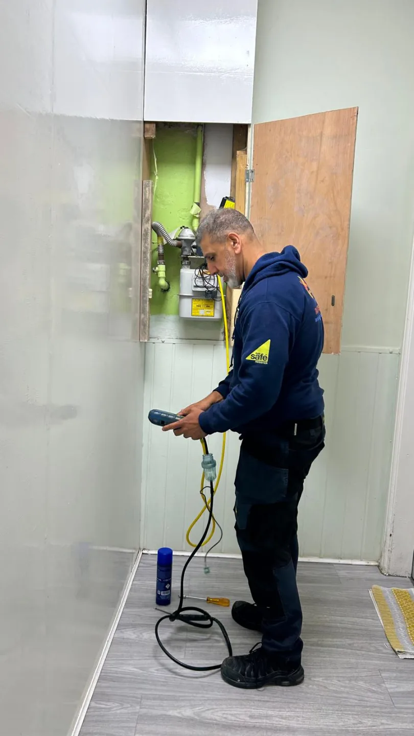 Gas Safe engineer in Gasmaster uniform testing a boiler in a domestic utility room