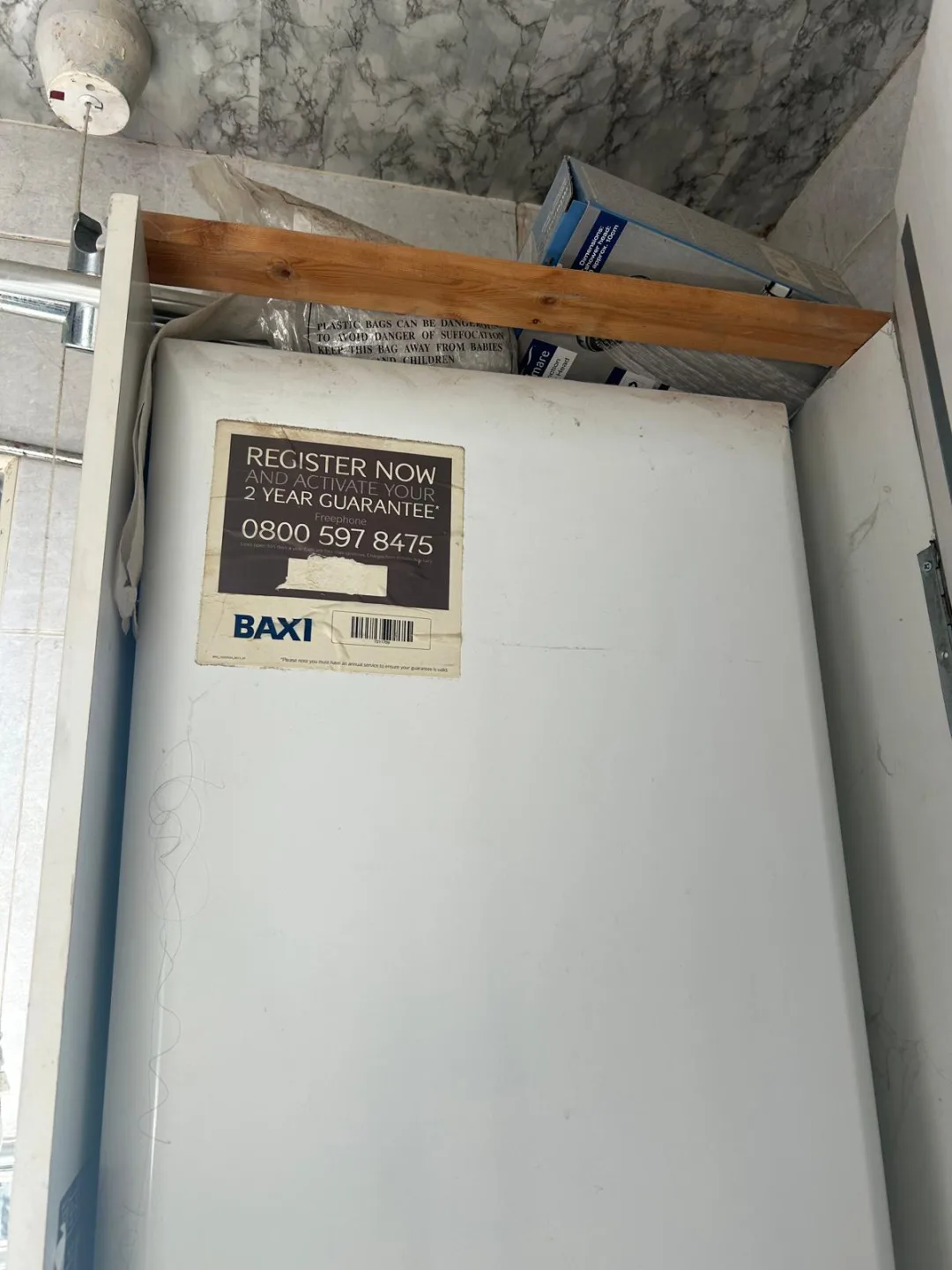 Baxi boiler inside a cupboard with its guarantee registration card attached