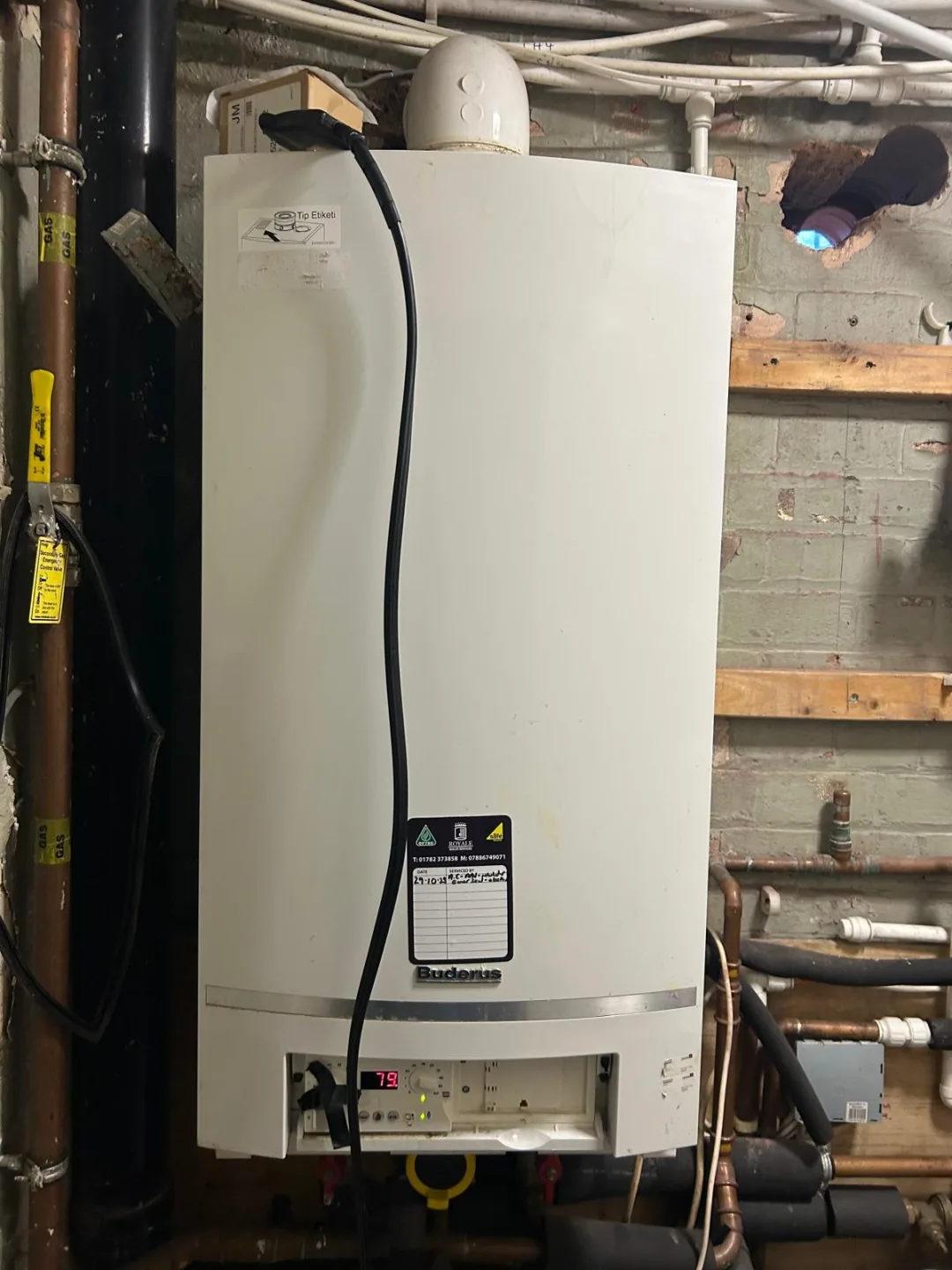 Boiler mounted in a cellar among timber joists and pipework