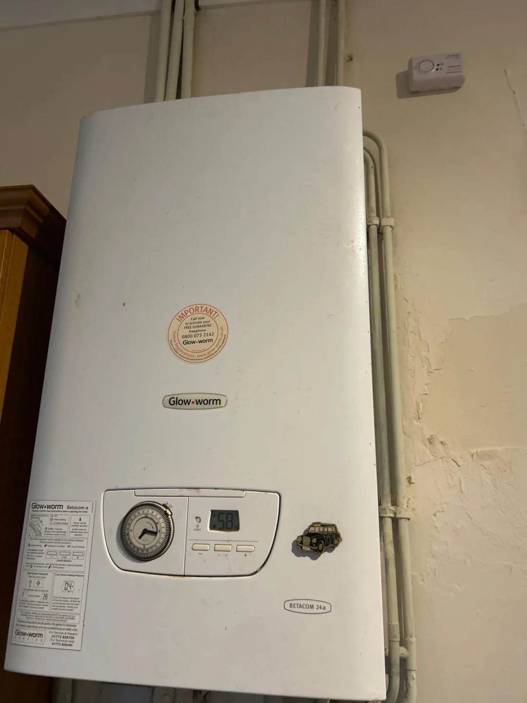 Older Glow-worm wall-mounted boiler with a pressure gauge on a painted wall